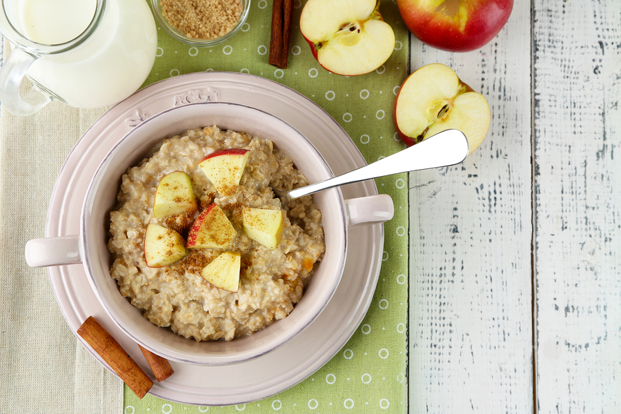 Tasty oatmeal with apples and cinnamon on wooden table